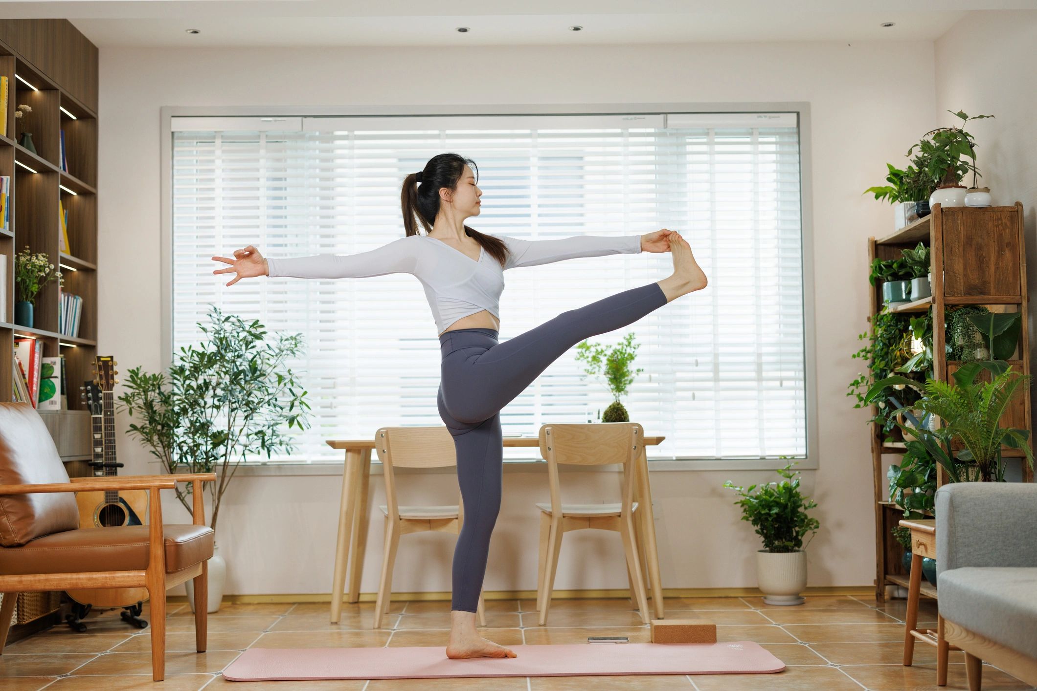 Woman stretching on a mat in a bright home workout space